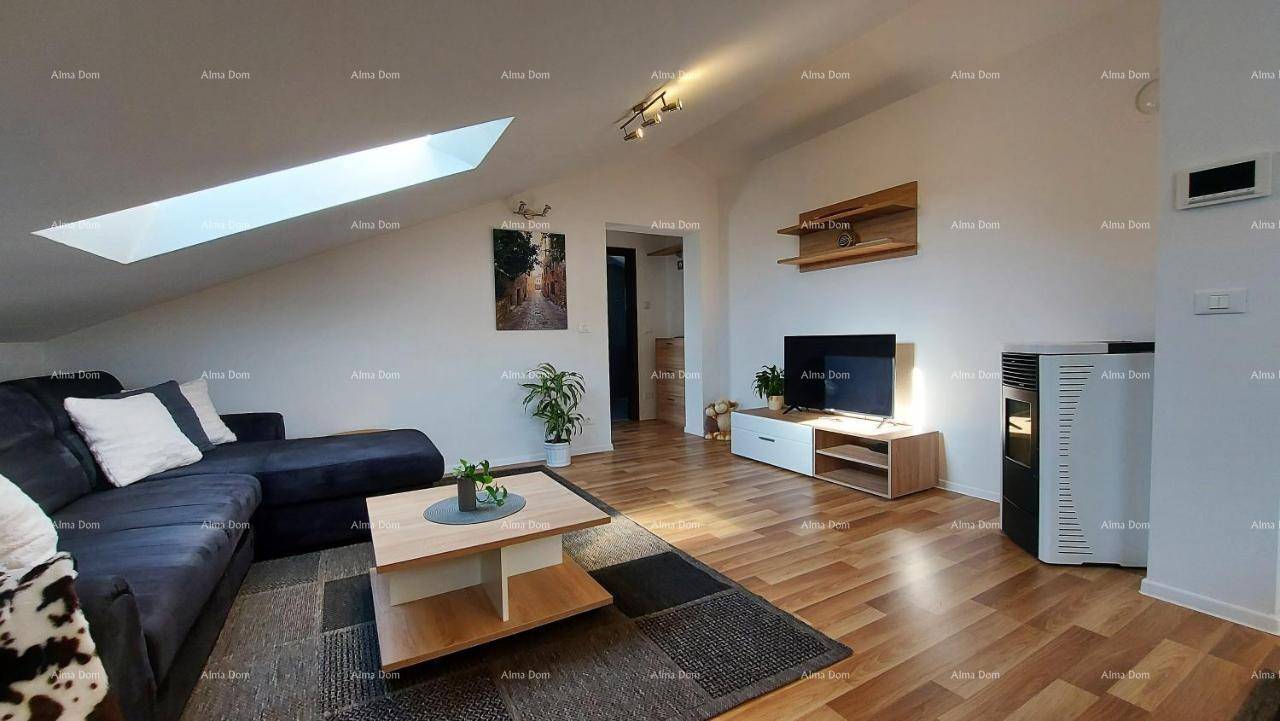 Heller Wohnbereich im Dachgeschoss mit Sofa, Fernseher und einem modernen Ofen.