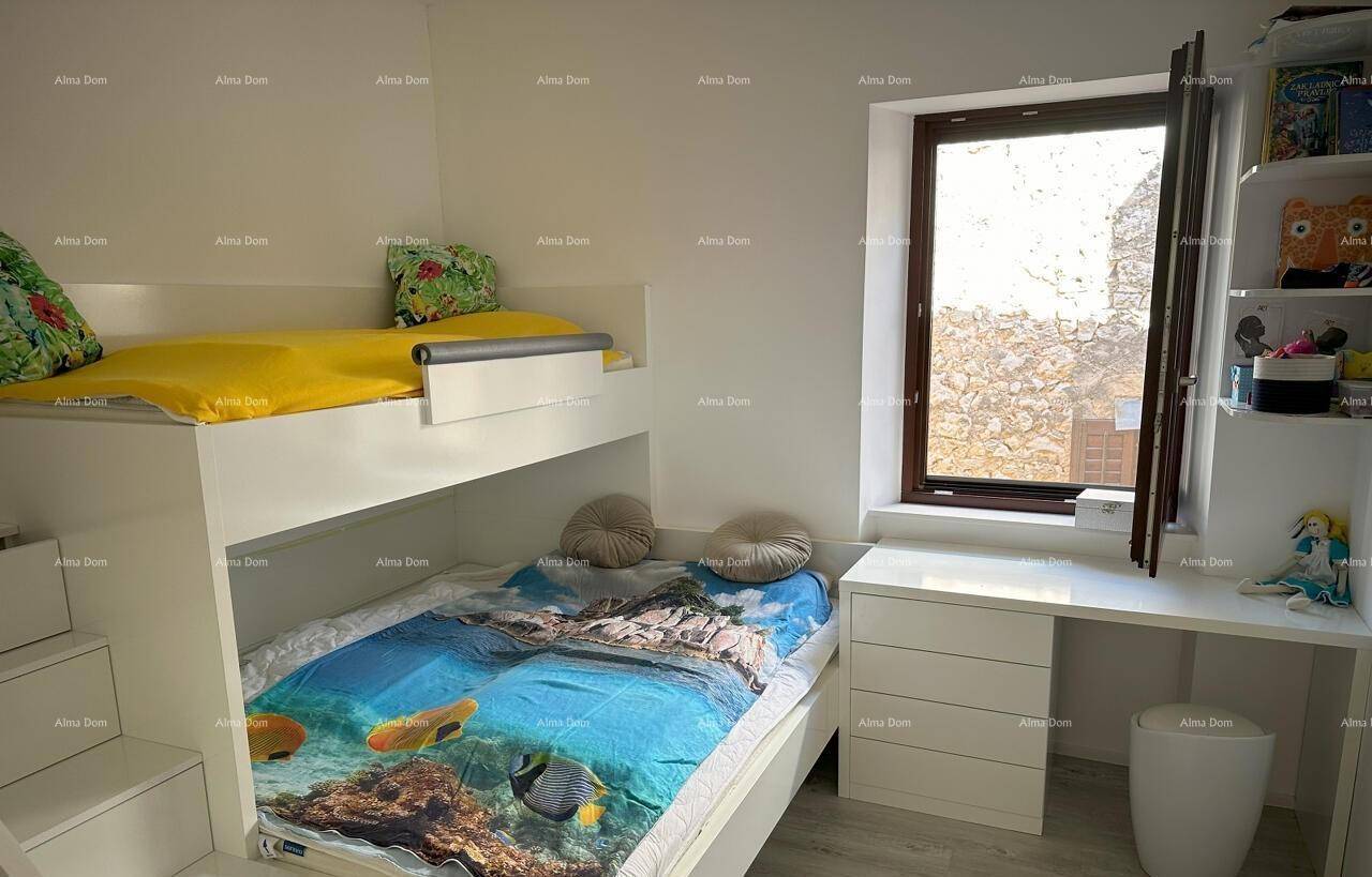 Kinderzimmer mit Etagenbett, Schreibtisch und einem Fenster, das viel Tageslicht hereinlässt.