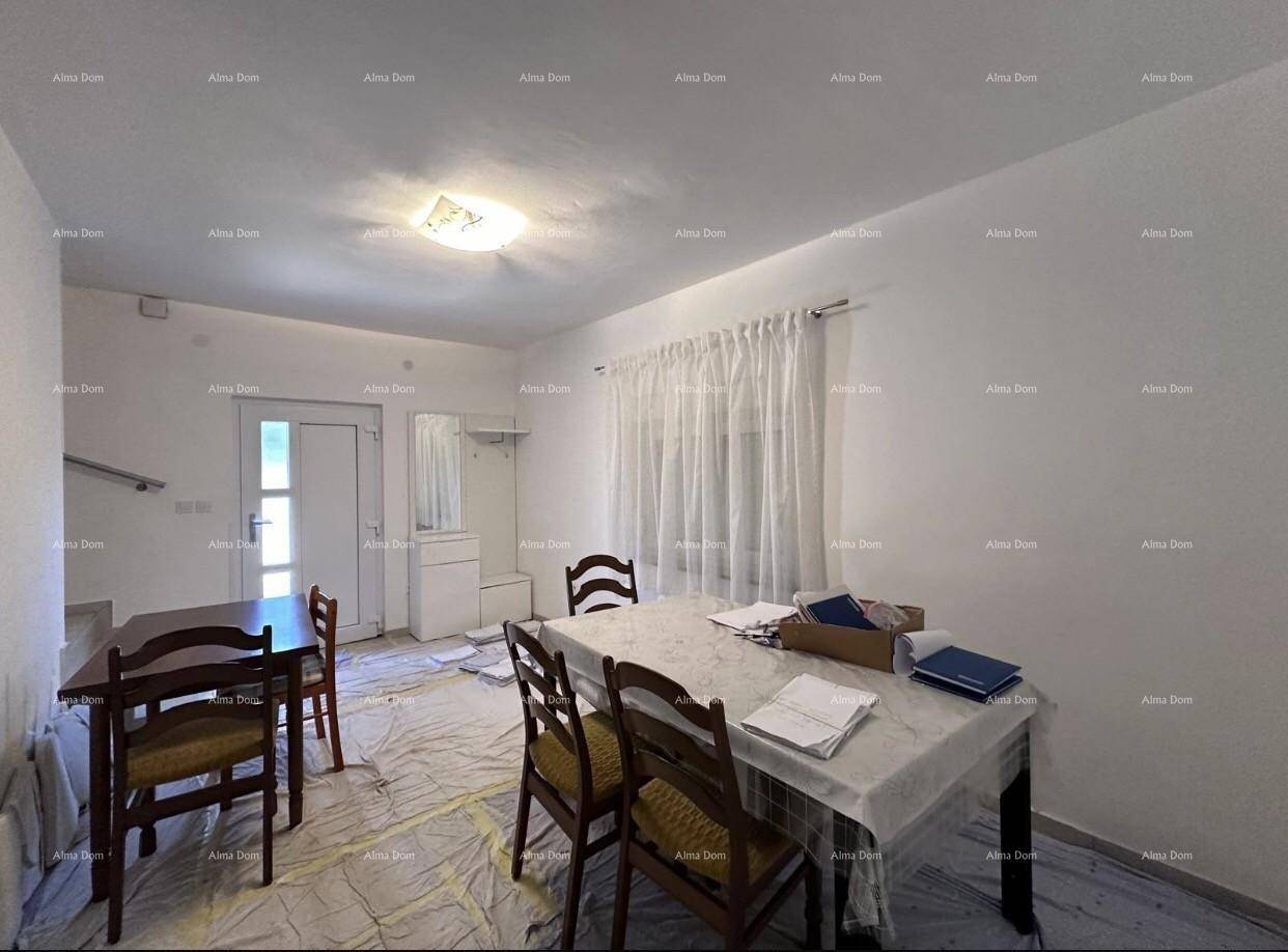Einfacher Essbereich mit Holztisch und Stühlen, nahe einem Eingangsbereich mit Garderobe.