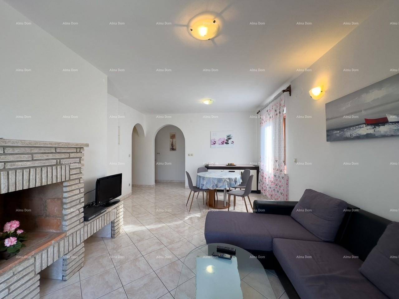Geräumiges Wohn-Esszimmer mit Kamin, Sofa und Essbereich, durch Bögen mit weiteren Räumen verbunden.