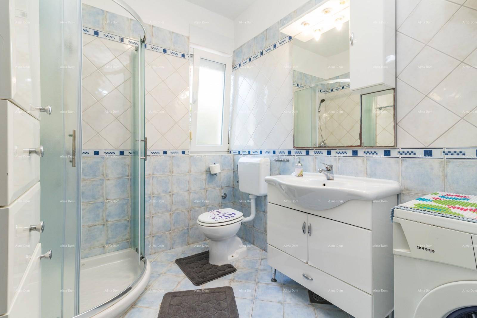 Badezimmer mit Duschkabine, WC, Waschbecken und blauen Fliesen im 80er-Jahre-Stil.