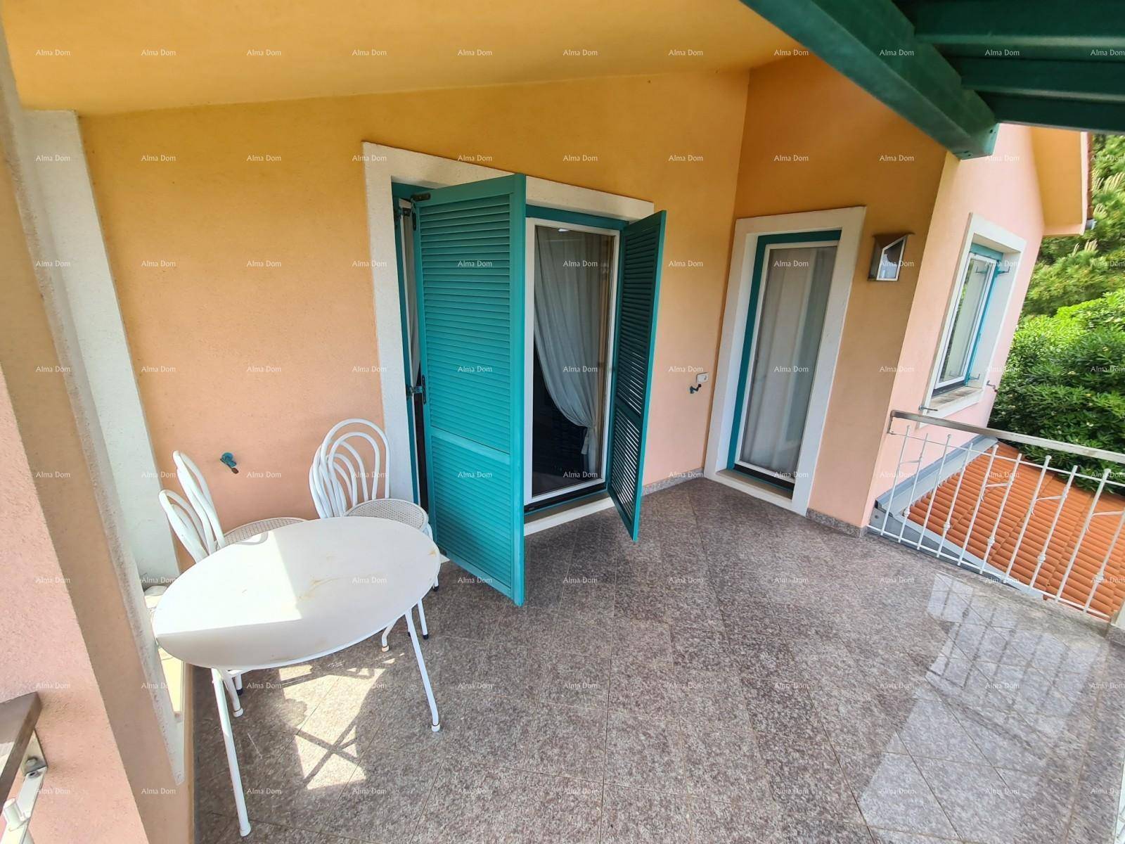 Geräumiger Balkon mit Outdoor-Möbeln und Fliesenboden, umgeben von grünen Bäumen.