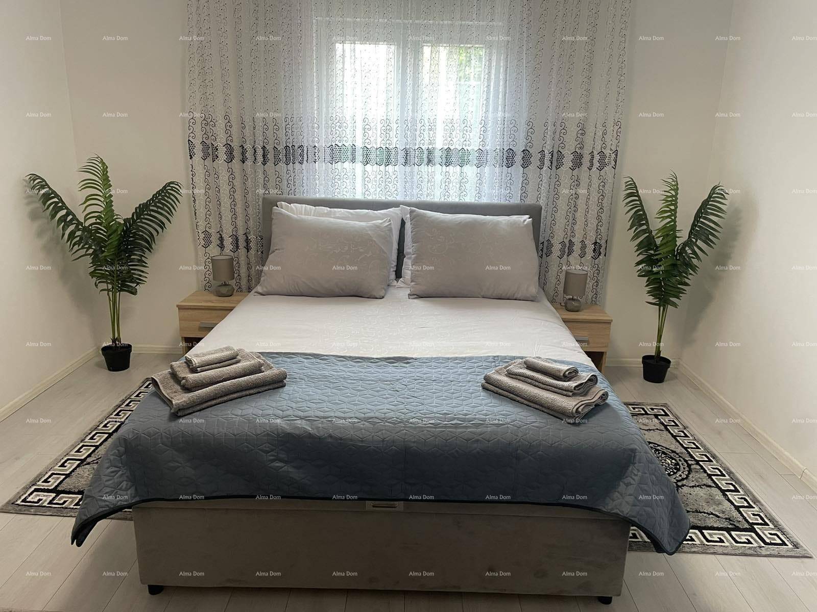 Gemütliches Schlafzimmer mit Doppelbett, Nachttischen, hellem Laminatboden und großen Fenstern.