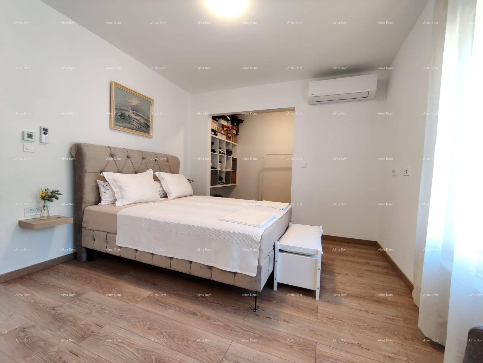Schlafzimmer mit Holzboden, großem Bett und offenem Zugang zu einem begehbaren Kleiderschrank.