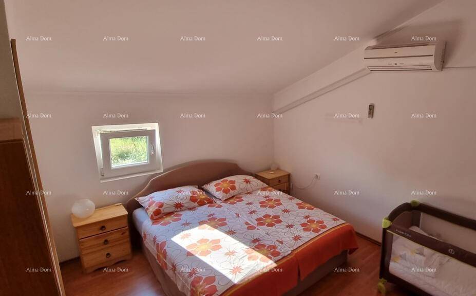 Helles Dachschlafzimmer mit Doppelbett, Nachttischen und Babybett unter der Dachschräge.
