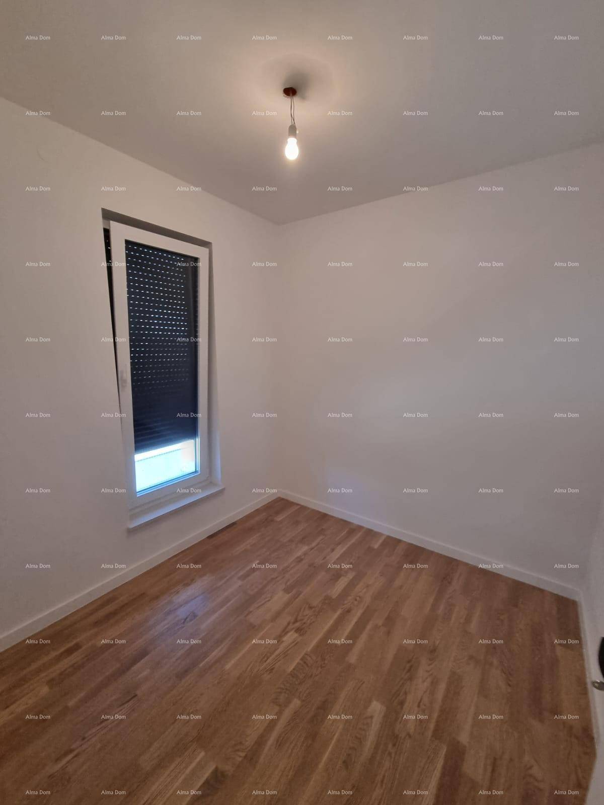 Helles Schlafzimmer mit warmem Holzparkett und einem Fenster mit integrierten Rollläden.