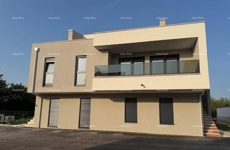 Moderne Gebäudefassade mit beiger Putzfassade, großen Fenstern und einem Balkon mit Glasgeländer.