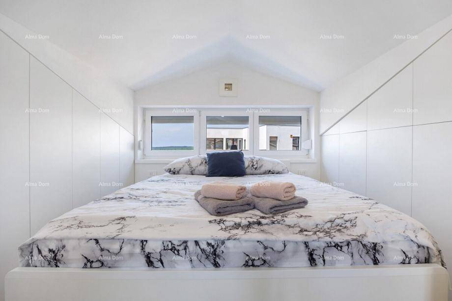 Schlafzimmer mit großem Bett, Fenster und integrierten Schränken unter dem Schrägdach.