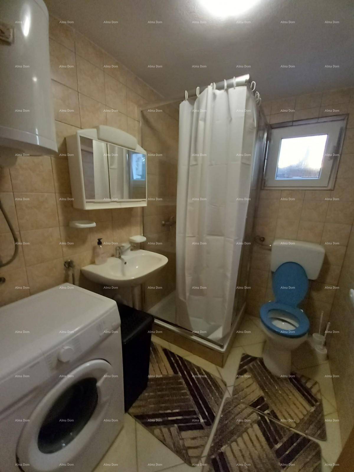 Gefliestes Badezimmer mit Dusche, WC, Waschbecken und Warmwasserboiler, in beigen Tönen.