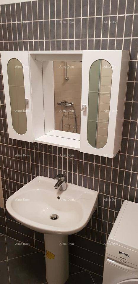 Detailansicht des Badezimmers mit Waschbecken, Spiegelschrank und Duschkopf in der Reflexion.