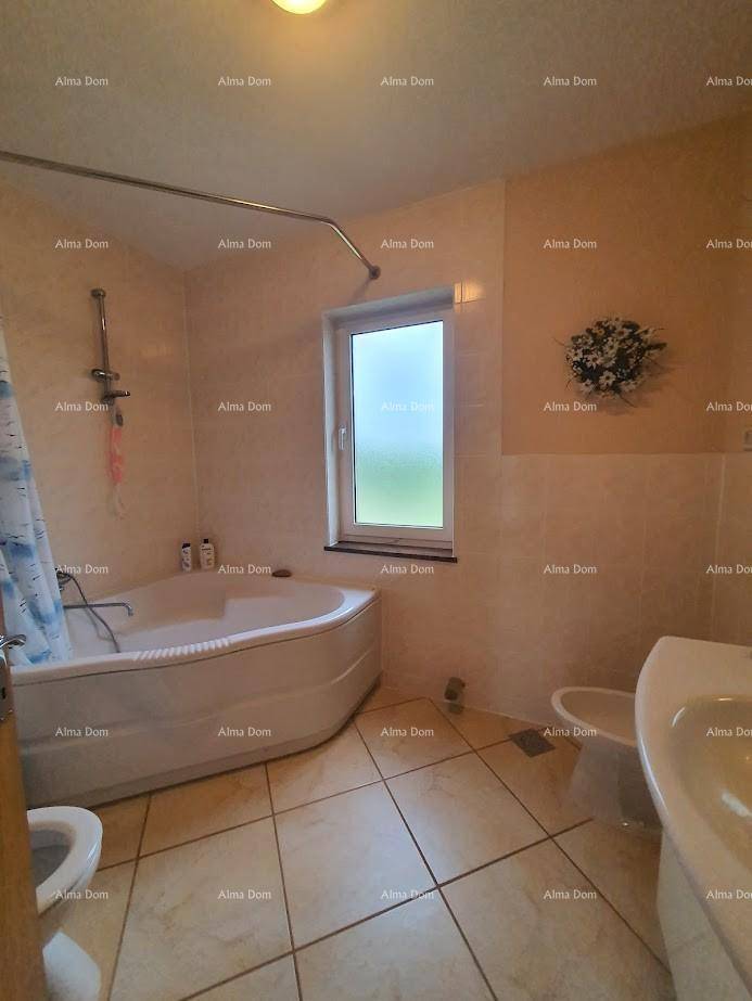 Badezimmer mit Eckbadewanne, Toilette, Waschbecken und Fenster.