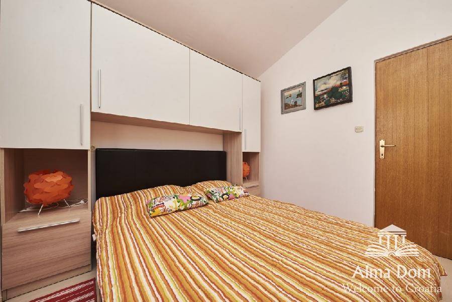 Schlafzimmer mit Doppelbett, Einbauschränken und Holztür.
