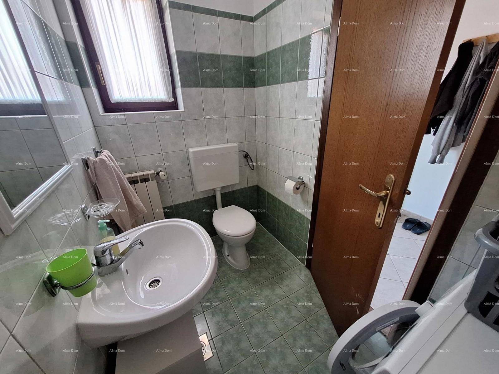 Kleines WC mit grün-weiß gefliesten Wänden und Fenster.