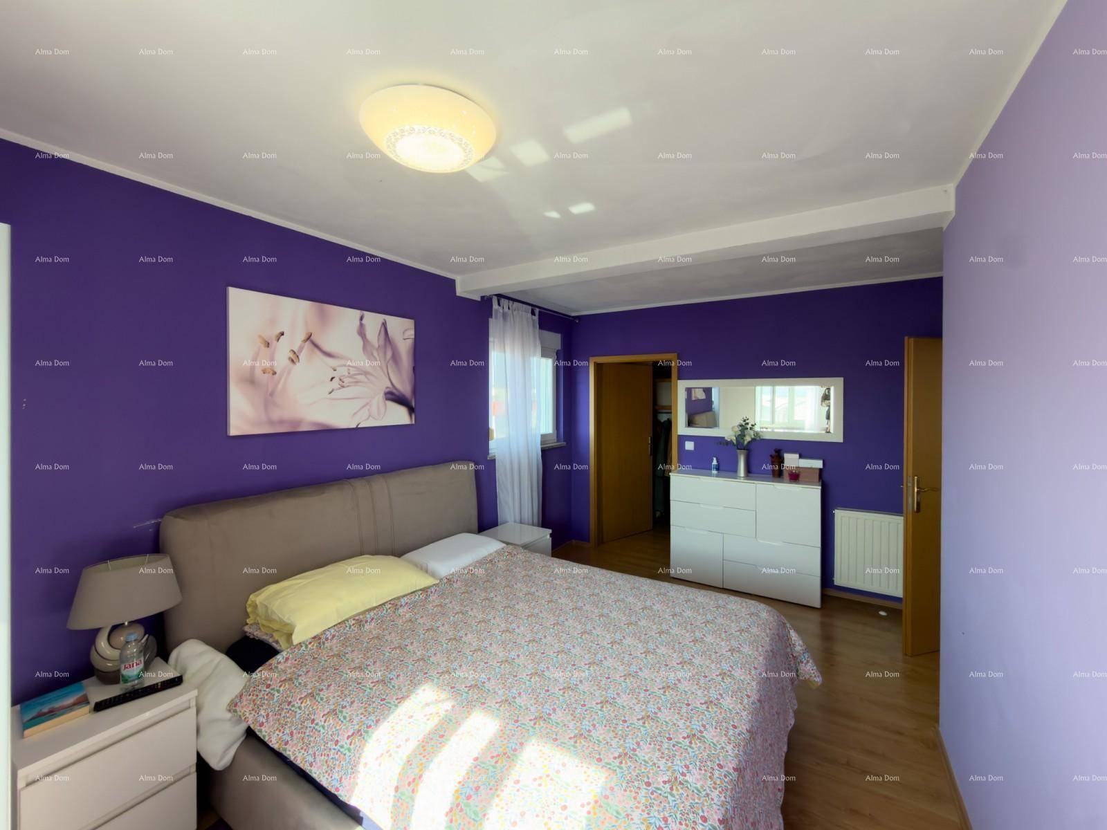 Geräumiges Schlafzimmer mit lila Akzentwänden, Doppelbett und Kommode.