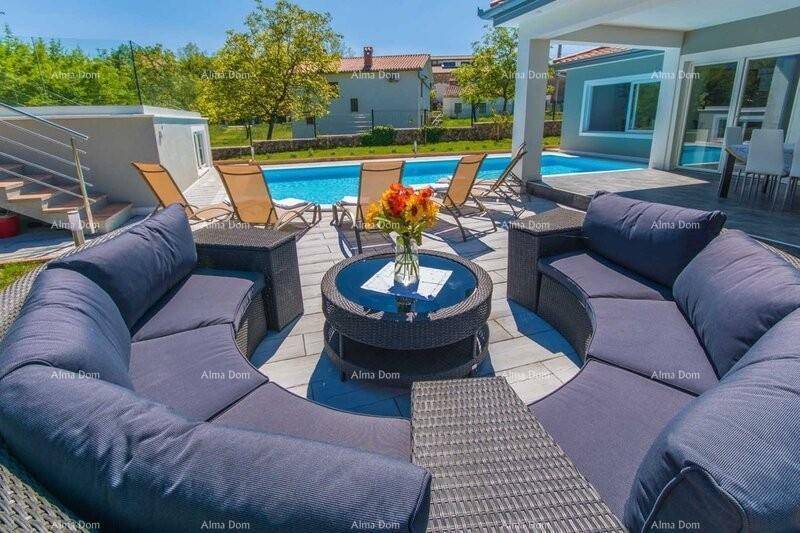 Gemütliche Lounge-Ecke auf der Terrasse mit Rattanmöbeln und Blick auf den Poolbereich.