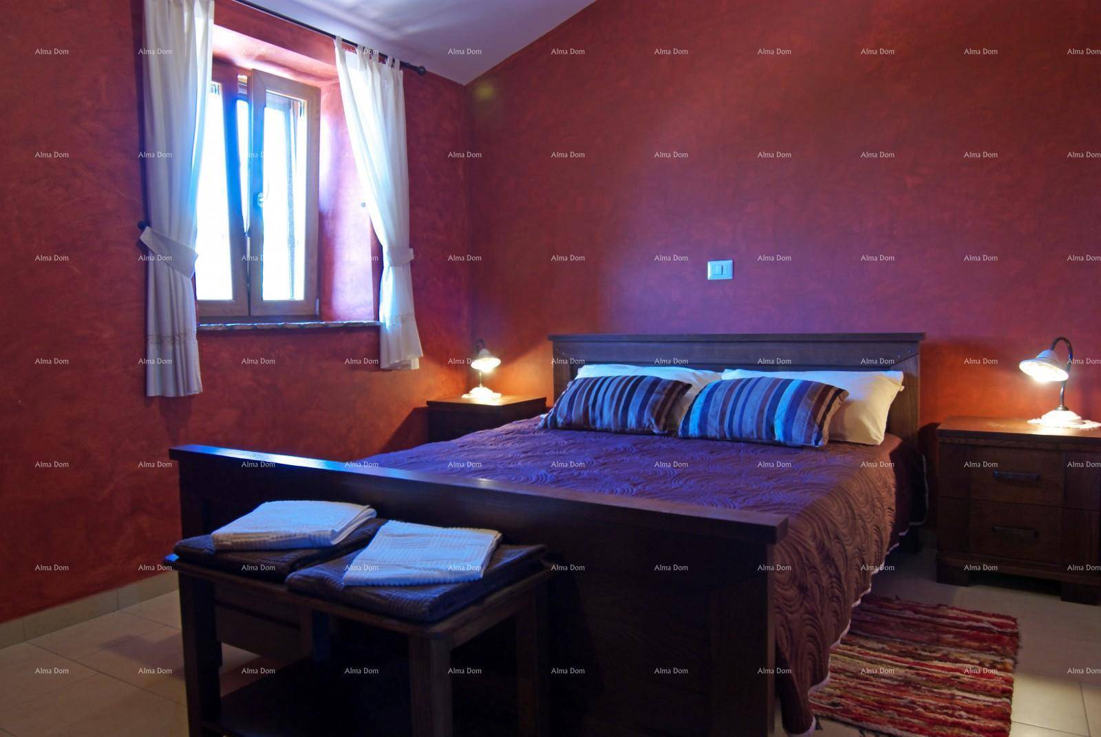 Schlafzimmer mit kräftigen roten Wänden, Holzbett und einem Fenster für natürliches Licht.