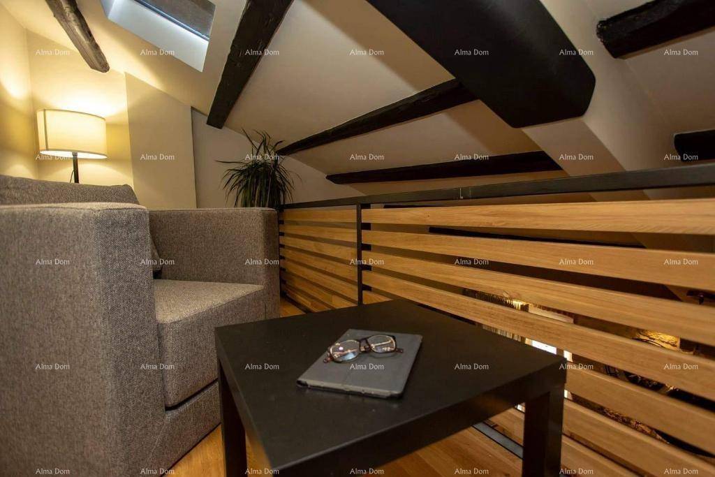 Gemütlicher Sitzbereich auf der Galerie mit Sessel und Couchtisch, unter sichtbaren Holzbalken und Dachfenster.