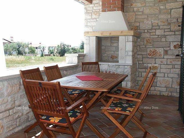 Überdachte Terrasse mit Steingrill, Holztisch und Stühlen, ideal für Mahlzeiten im Freien.