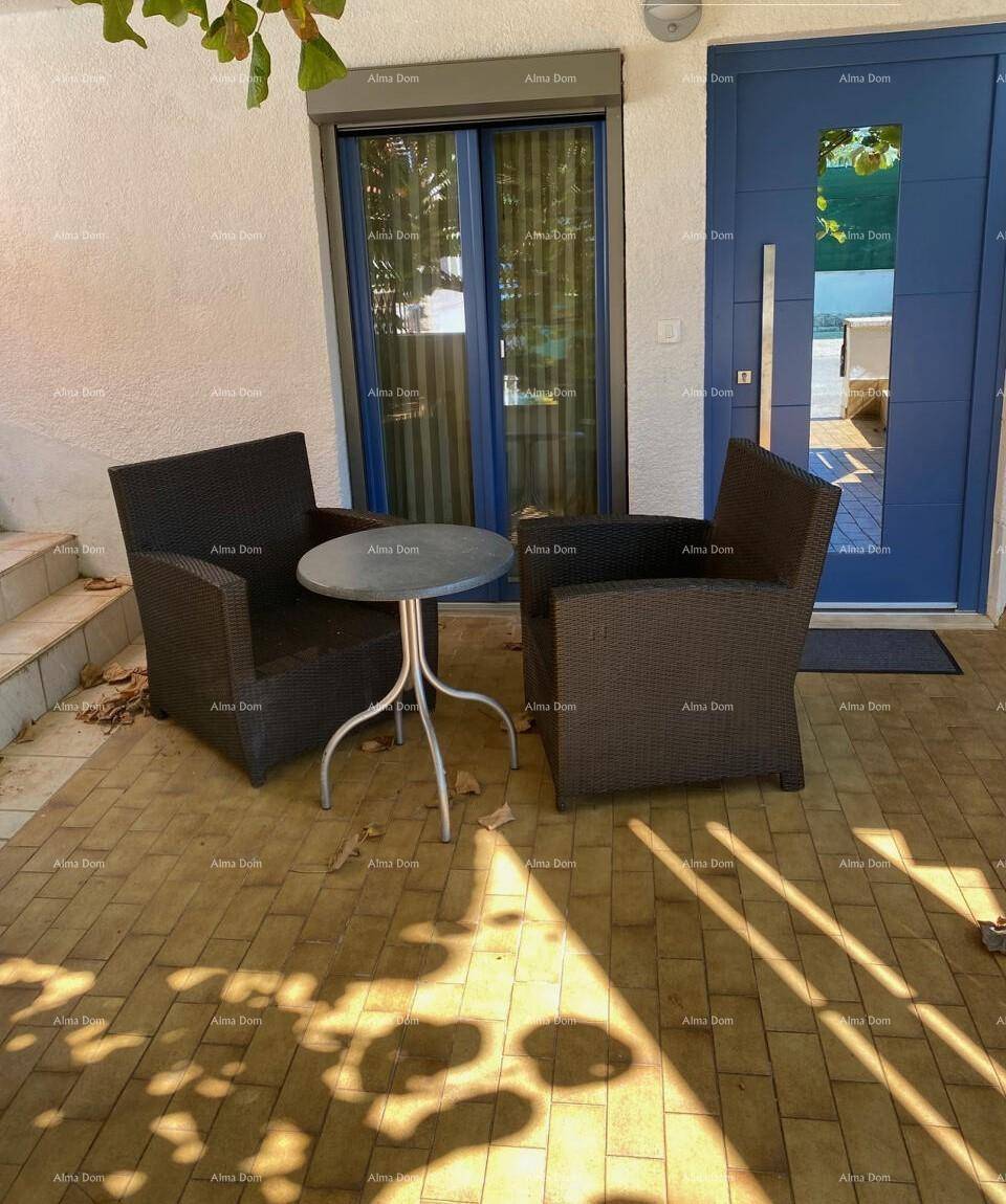 Einladender Terrassenbereich mit bequemen Korbsesseln und einem kleinen Tisch vor der blauen Eingangstür.