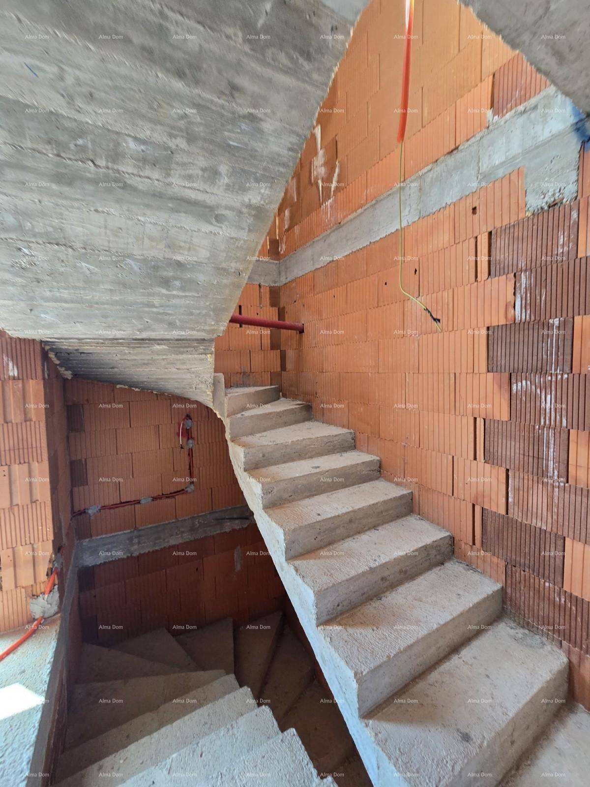 Treppenhaus im Rohbau mit unverputzten Ziegelwänden und Betondecken.