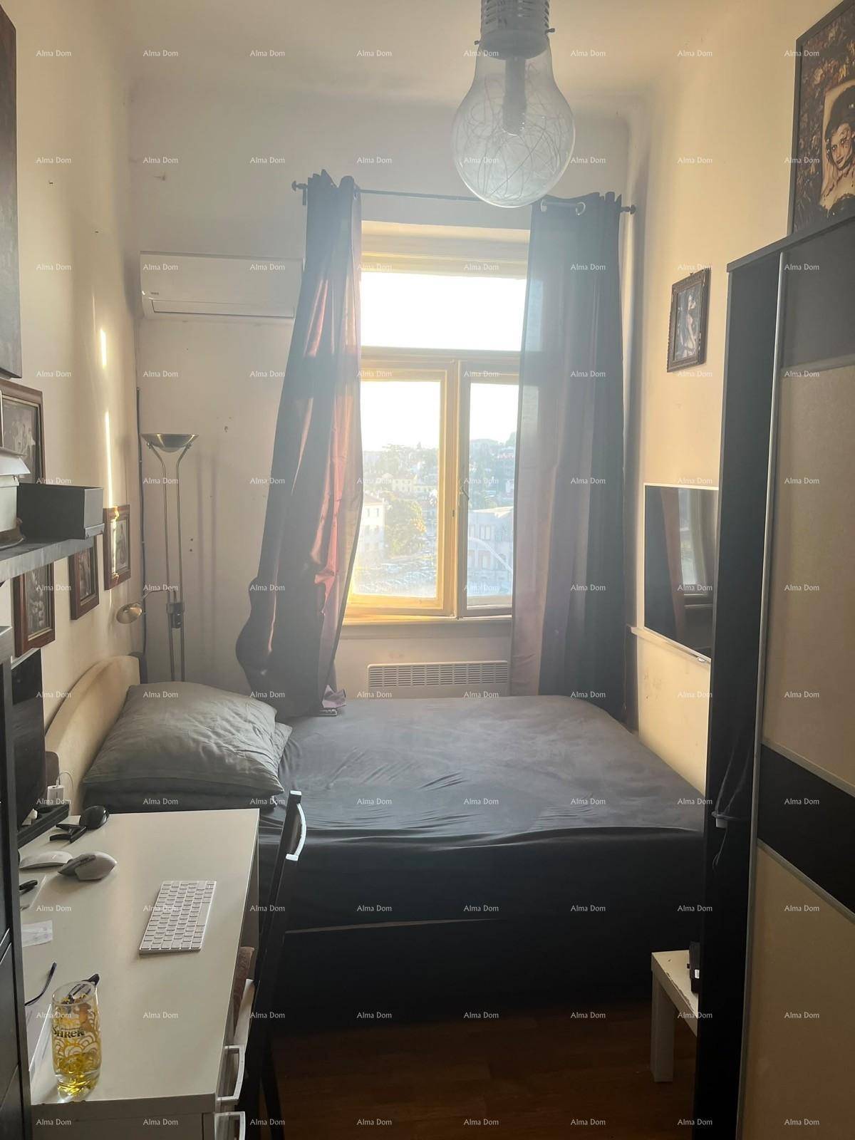 Kleines Schlafzimmer mit Bett, Schreibtisch und Klimaanlage, hell durch das Fenster.