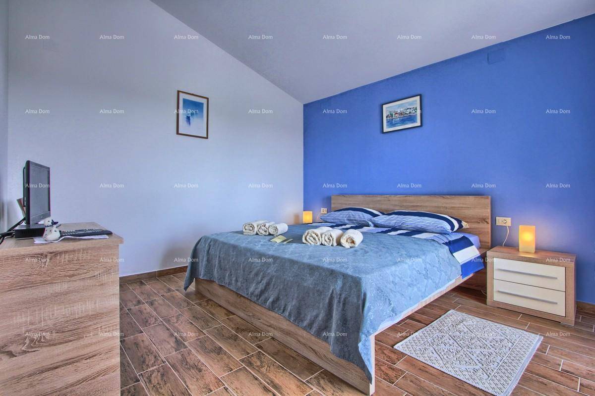 Schlafzimmer mit Doppelbett, blauer Akzentwand und Fliesen in Holzoptik.