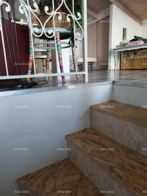 Innentreppe mit dekorativem, weißem Geländer, die zu einem oberen Bereich mit Dachschräge führt.