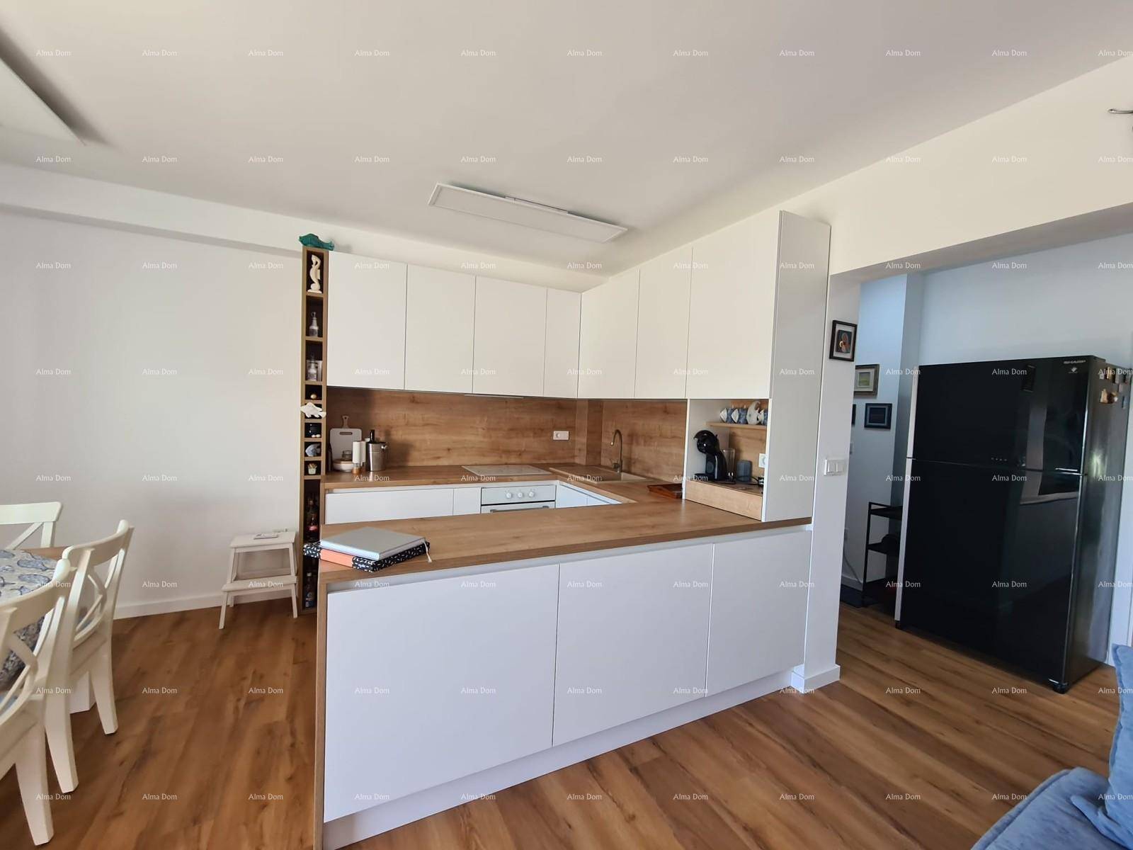 Moderne Küche mit weißen Schränken, Holz-Arbeitsplatten und integrierten Geräten, inklusive schwarzem Kühlschrank.