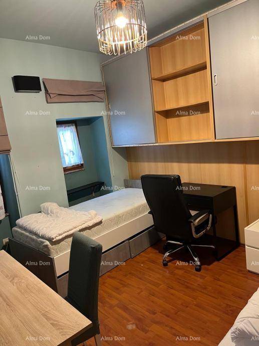 Schlafzimmer mit Einzelbett, Schreibtisch und Fenster, das Tageslicht hereinlässt.