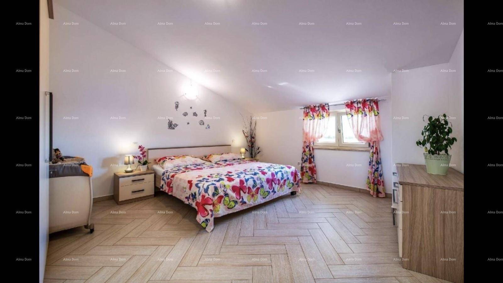 Helles Schlafzimmer mit Holzboden, großem Bett und Fenster mit bunten Vorhängen.