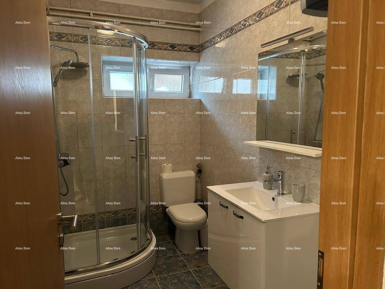 Funktionales Badezimmer mit Duschkabine, WC, Waschbecken und Fliesen an Wänden und Boden.
