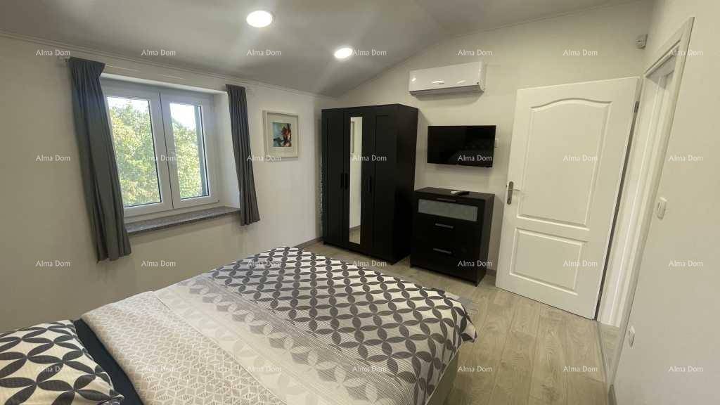 Helles Schlafzimmer mit Doppelbett, Kleiderschrank, Klimaanlage und Holzboden.