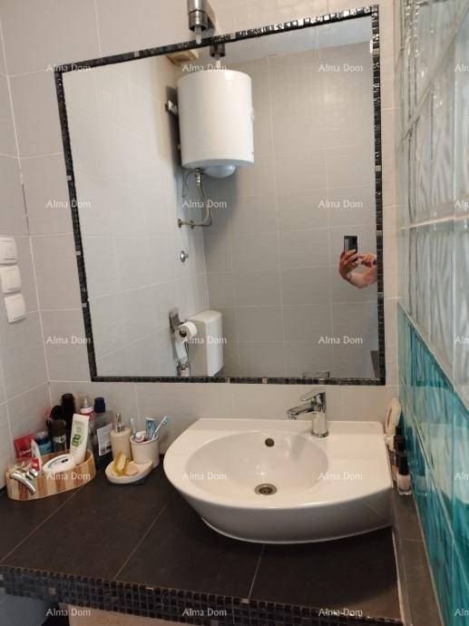 Badezimmer mit einem einzelnen Waschbecken, großem Wandspiegel und einem sichtbaren Warmwasserboiler.