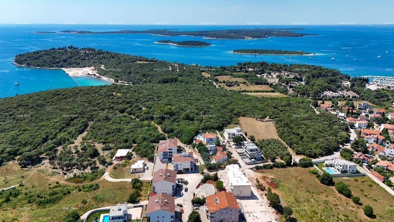 Weitläufige Luftaufnahme einer Küstenregion mit Wohngebieten, viel Grün und Inseln im blauen Meer.