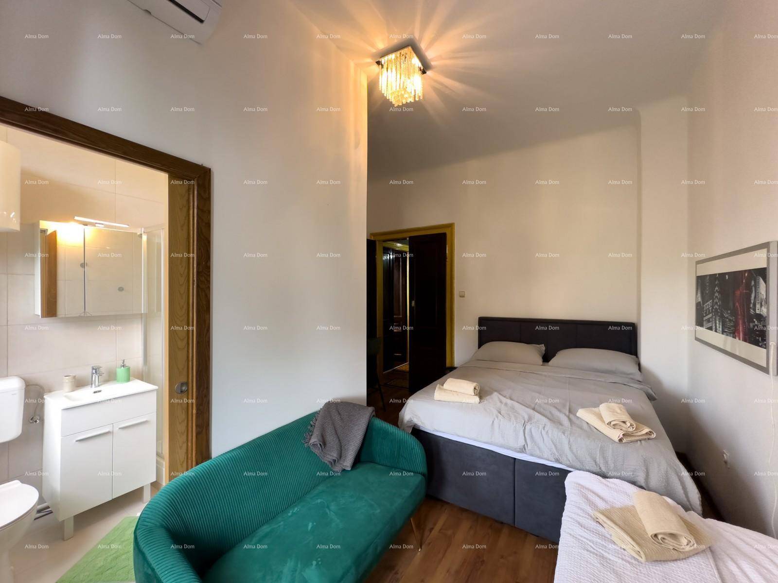 Schlafzimmer mit Doppelbett, grünem Sofa und direktem Zugang zu einem modernen Badezimmer.