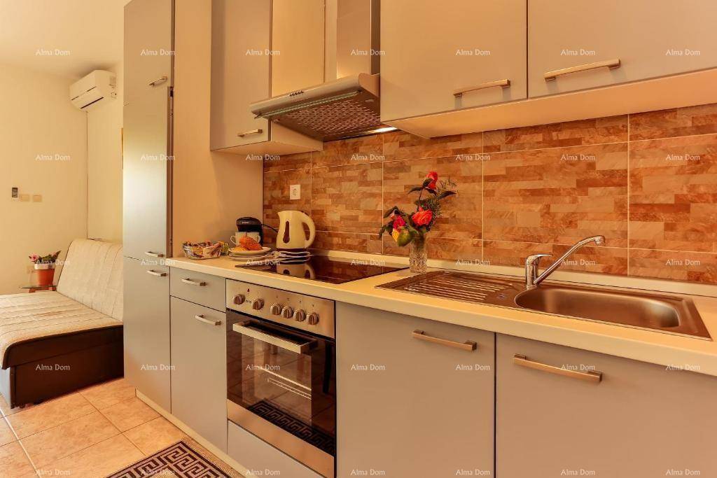 Moderne Küche mit grauen Schränken, Backofen und Kochfeld.