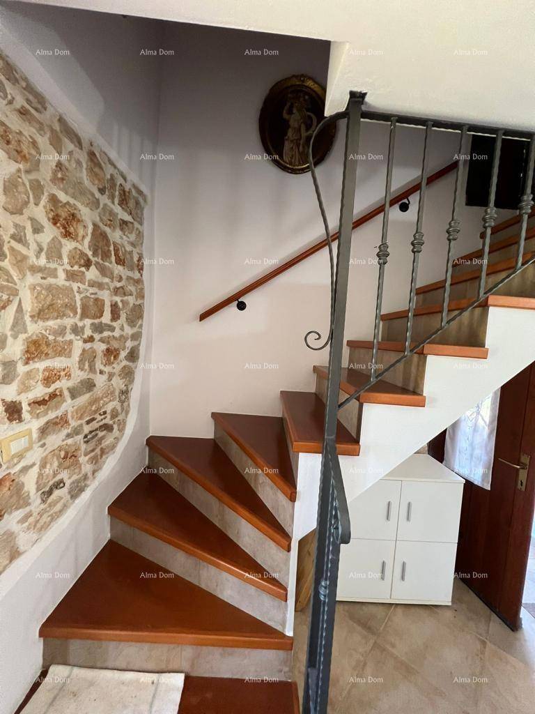 Holztreppe mit schmiedeeisernem Geländer und freigelegter Steinwand.