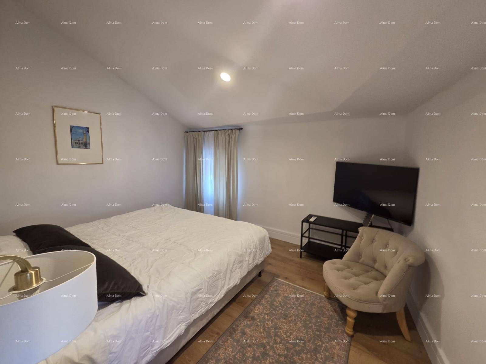Gemütliches Schlafzimmer mit Bett, Sessel und Wandfernseher unter einer leicht schrägen Decke.
