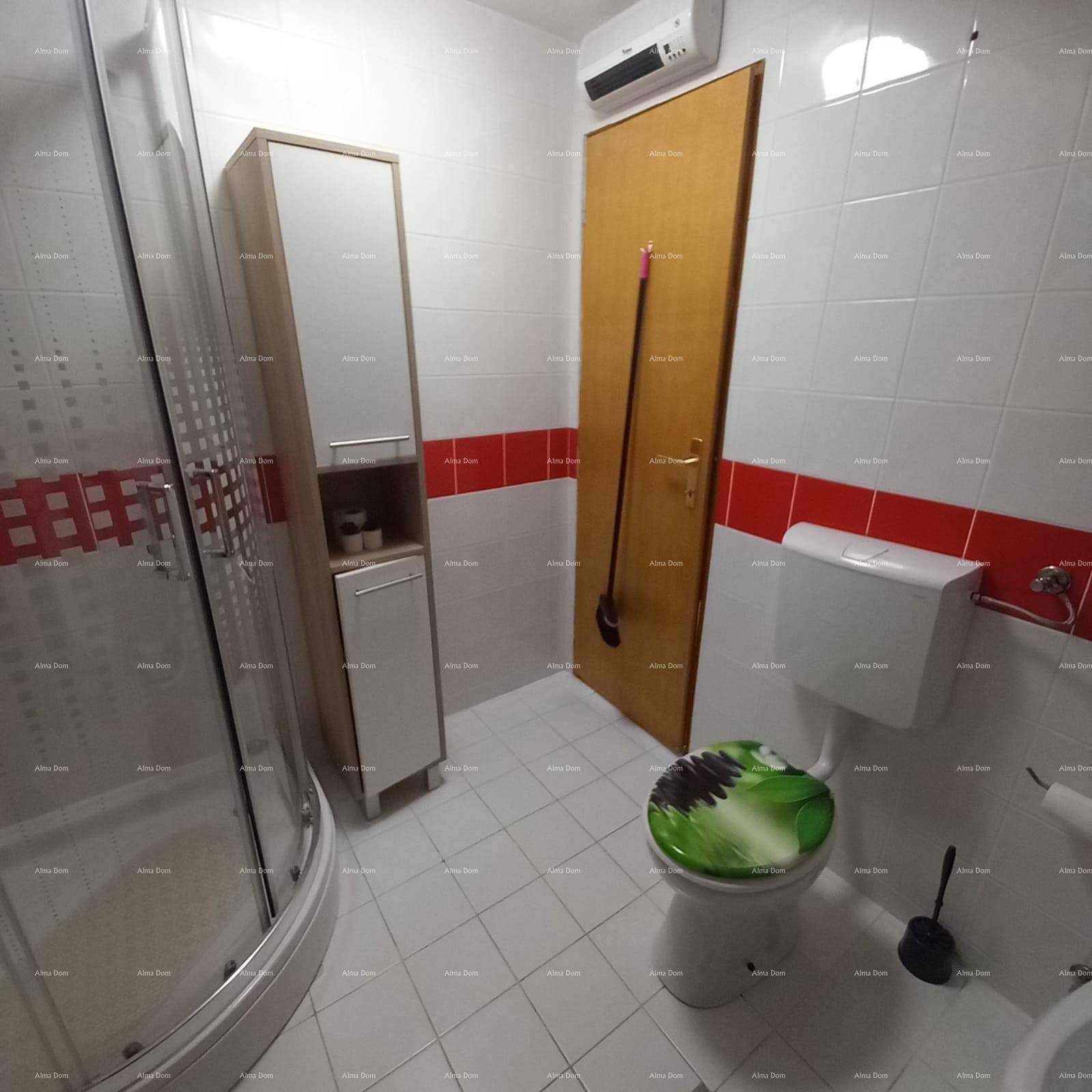 Gefliestes Badezimmer mit Duschkabine, WC, Waschbecken und Klimaanlage.