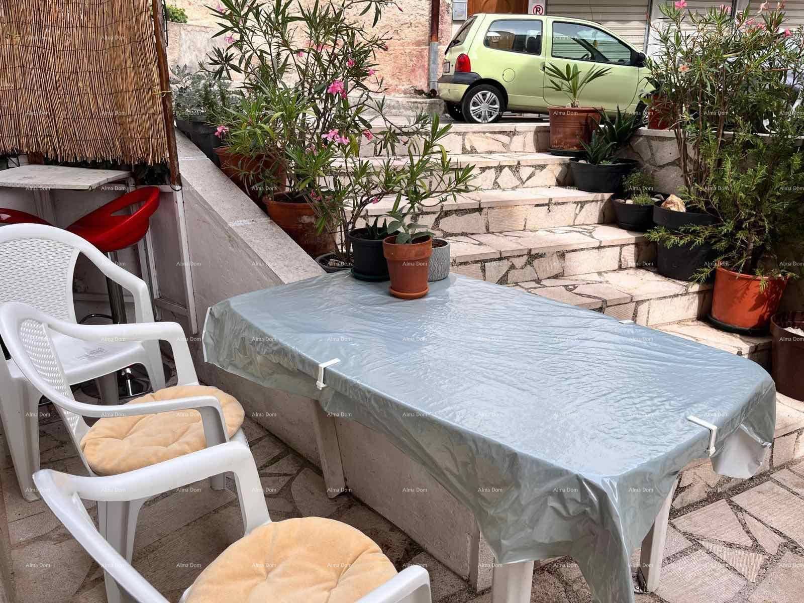 Gemütliche Außenterrasse mit Tisch und Stühlen, umgeben von Topfpflanzen und Steinstufen.