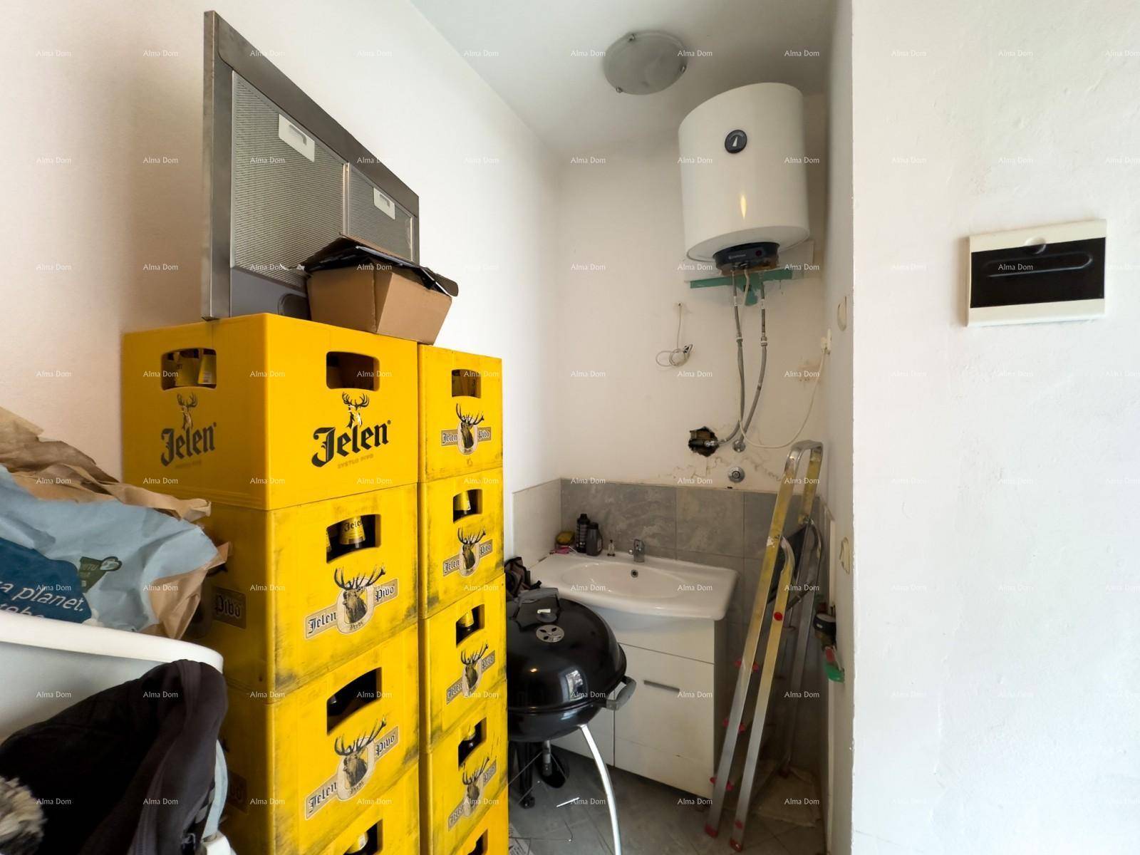Hauswirtschaftsraum mit Warmwasserbereiter, Waschbecken und Lagerkisten.