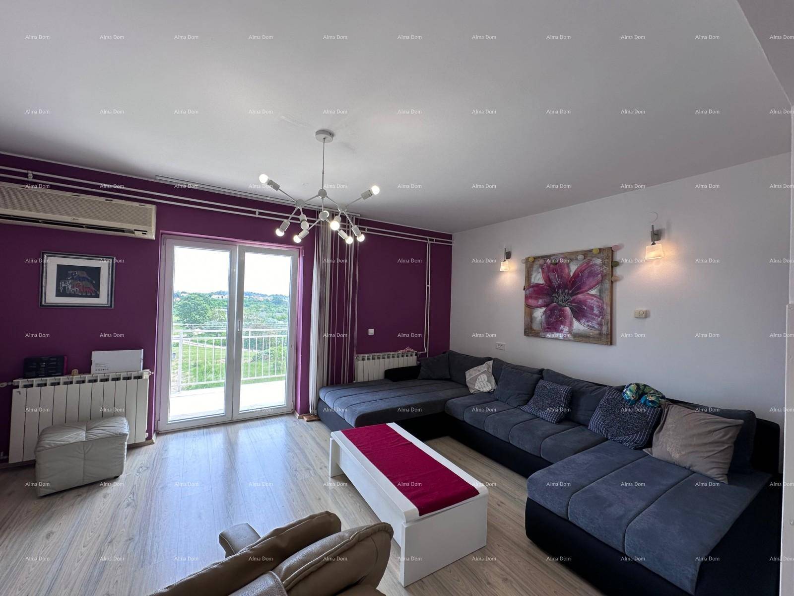 Lichtdurchflutetes Wohnzimmer mit großem Sofa, lila Wänden und Zugang zum Balkon.