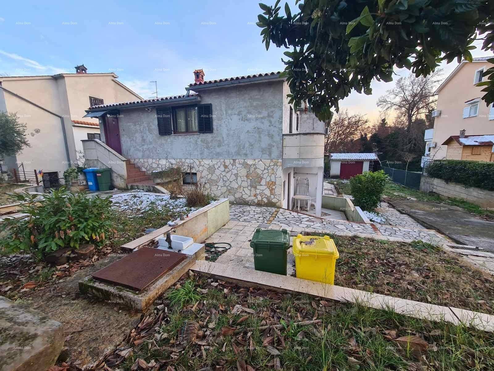 Hausfassade mit Steinfassade, Gartenbereich mit Mülltonnen und einem gepflasterten Weg.