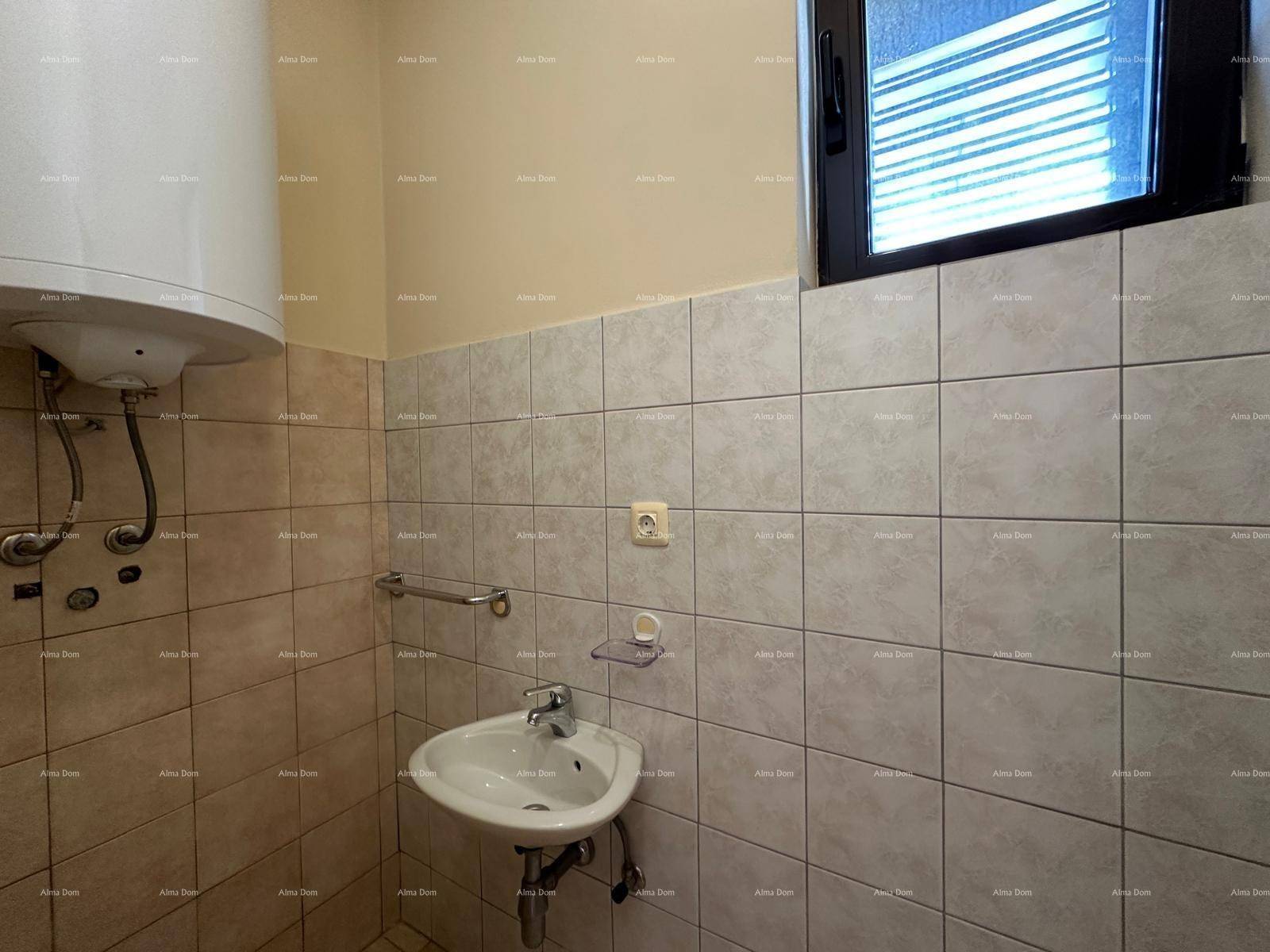 Kleines Badezimmer mit Waschbecken, Warmwasserboiler und hellen Fliesen an den Wänden.