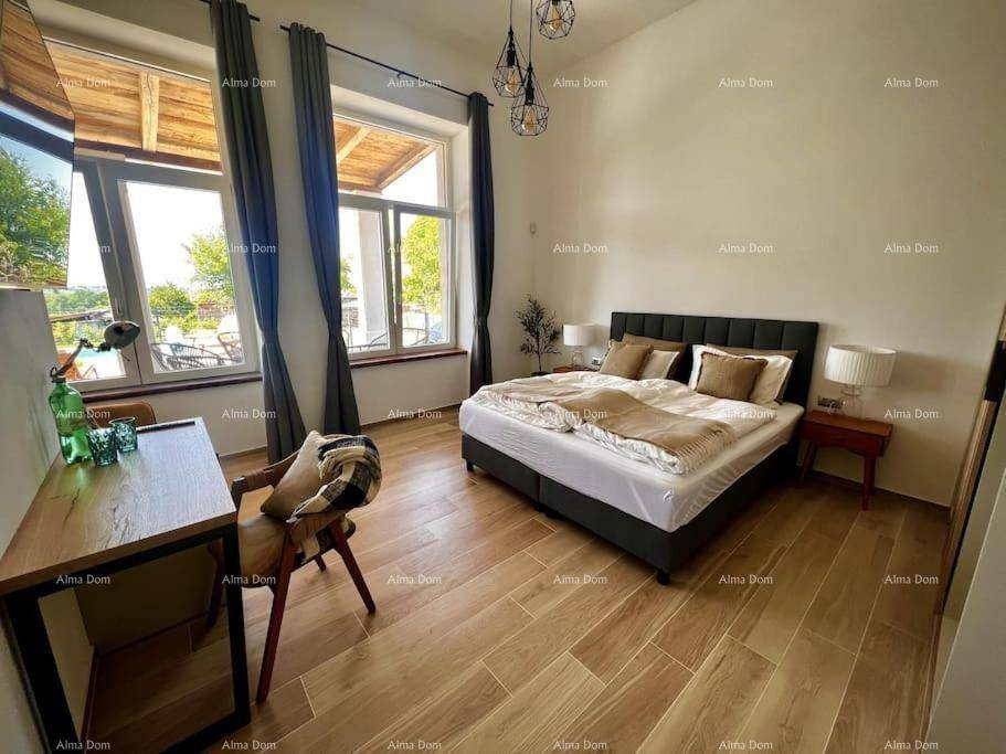 Komfortables Schlafzimmer mit Holzboden, Schreibtisch und Blick auf die Terrasse.