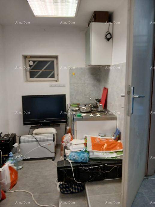 Kleine Küchenzeile mit Spüle, Kühlschrank und Fernseher in einem beengten Raum.