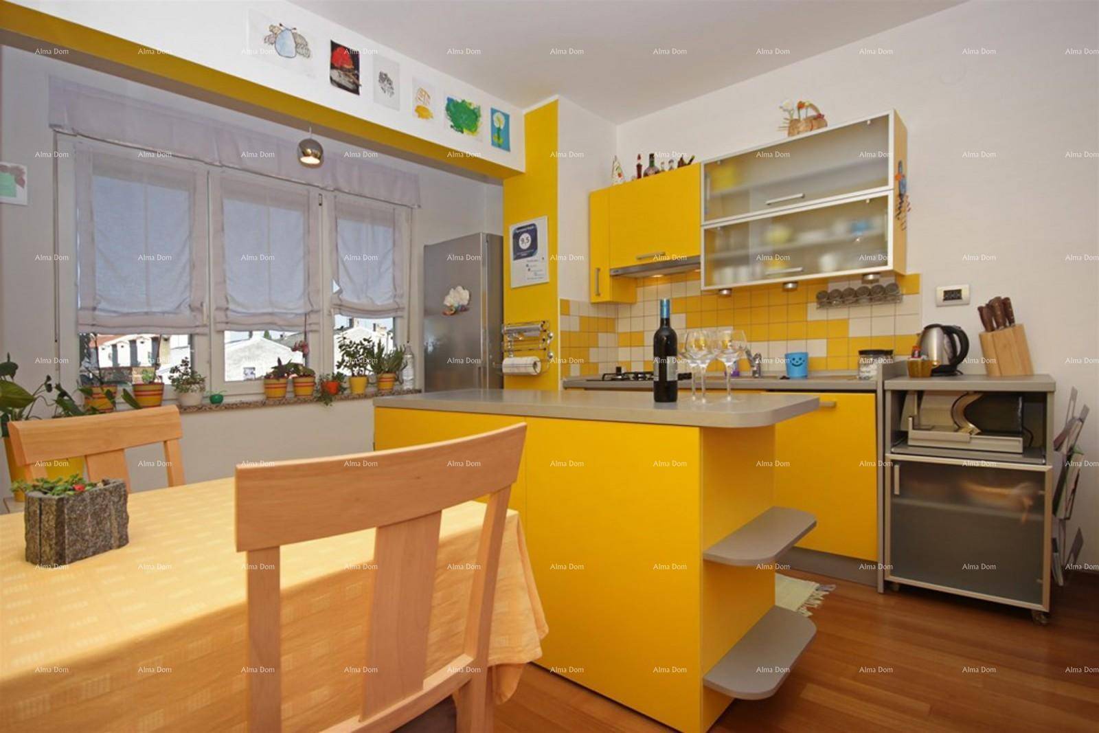 Helle Küche mit gelben Schränken, Essbereich und Fenster mit Pflanzen.