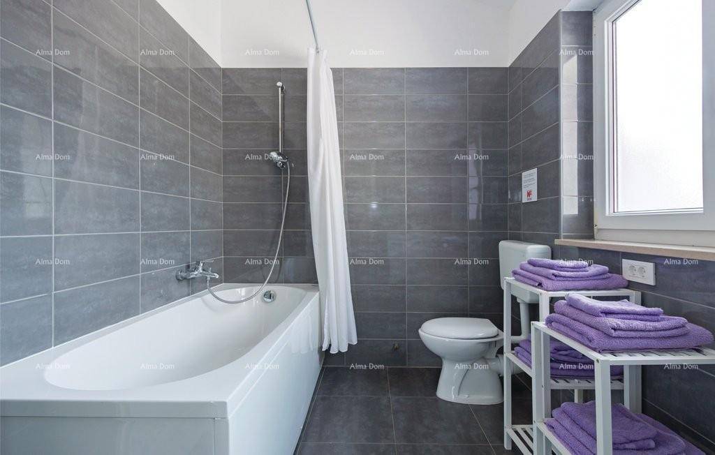 Modernes Badezimmer mit grauen Fliesen, Badewanne und Fenster für Tageslicht.