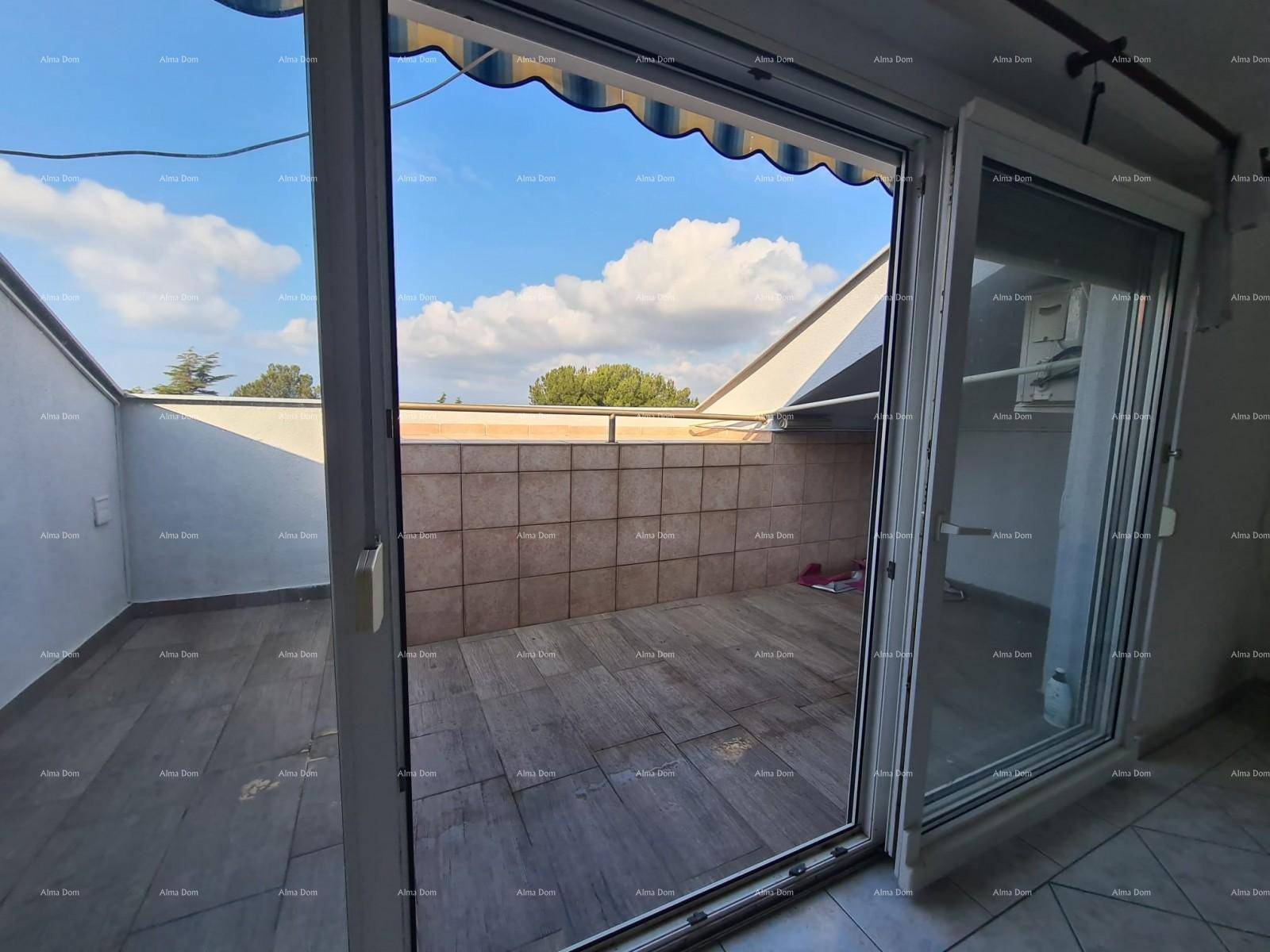 Blick von einem Innenraum auf eine geräumige, geflieste Terrasse mit Markise und weitem Himmel.