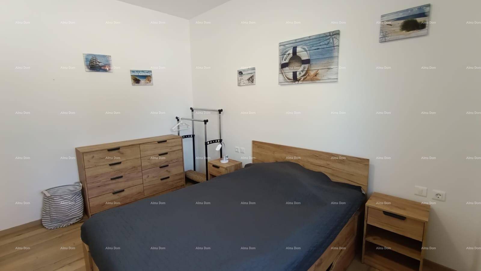 Helles Schlafzimmer mit Holzbett, Kommode und maritimen Wandbildern.